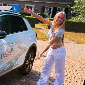 Leerling poseert vrolijk bij de lesauto van Rijschool Lieke
