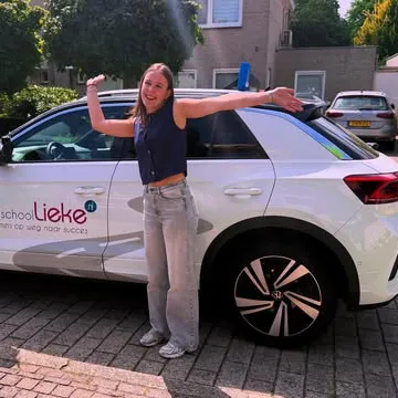 Leerling poseert bij de lesauto van Rijschool Lieke