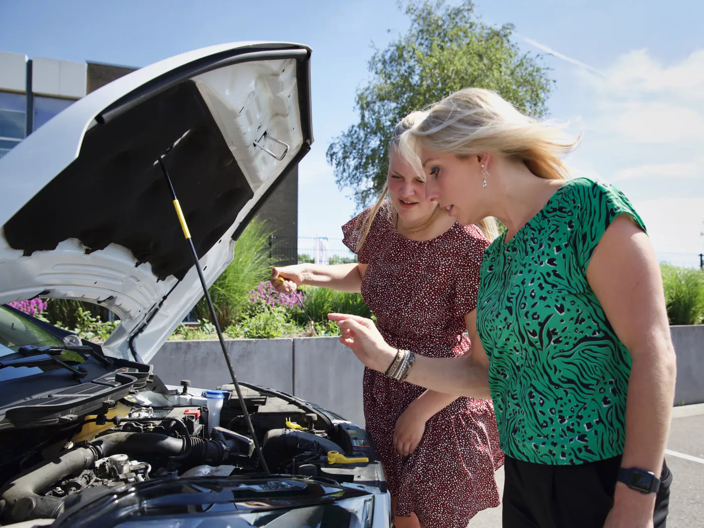 Lieke legt een leerling uit hoe je de motorkap van de lesauto controleert